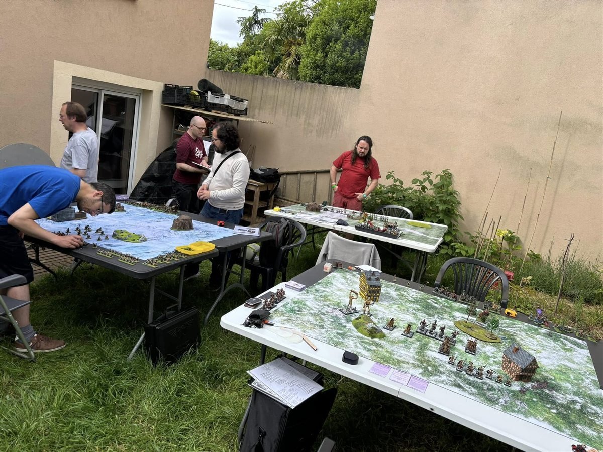 Vue generale d'une journee de jeu avec plusieurs tables de wargame